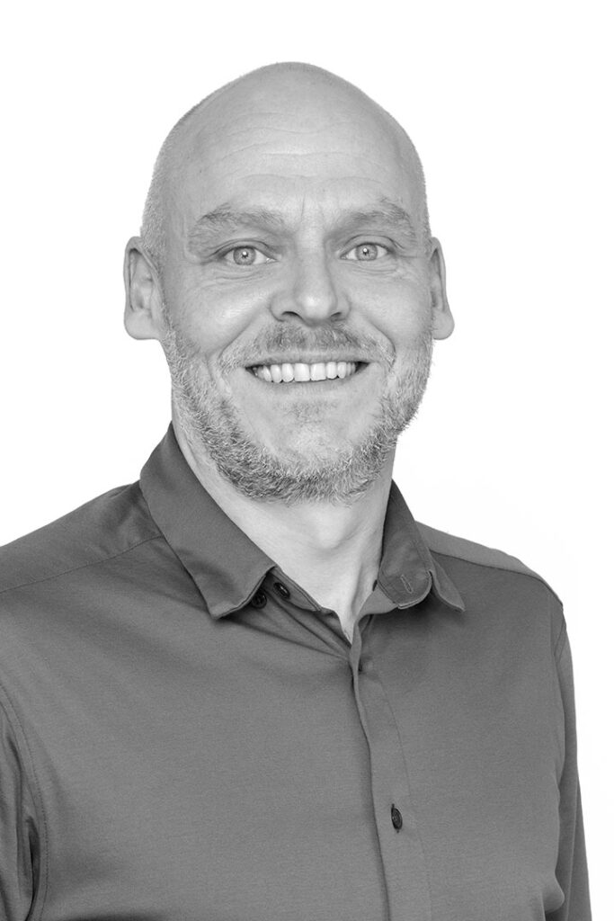 Portrætfoto i sort / hvid af salgssupport i Lithomex Jan Guldberg Pedersen i skjorte på hvid baggrund